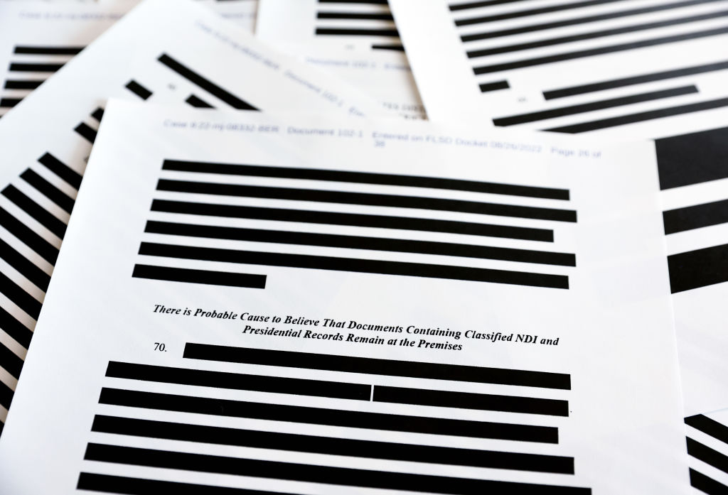 In this photo illustration, pages are viewed from the government’s released version of the F.B.I. search warrant affidavit for former President Donald Trump's Mar-a-Lago estate on August 27, 2022 in California. The 32-page affidavit was heavily redacted for the protection of witnesses and law enforcement and to ensure the ‘integrity of the ongoing investigation’.