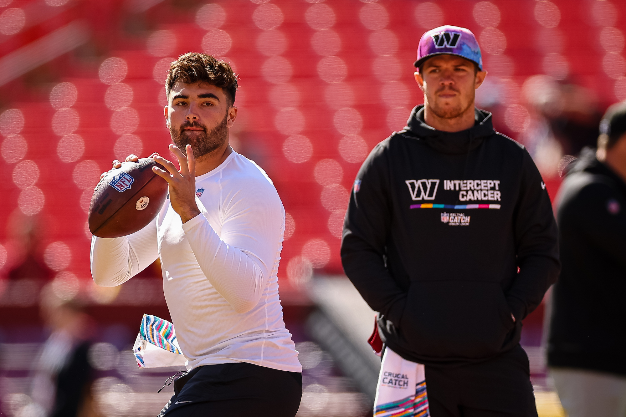 LANDOVER, MD - OCTOBER 09: Sam Howell #14 of the Washington Commanders warms up as Taylor Heinicke #4 looks on before the game against the Tennessee Titans at FedExField on October 9, 2022 in Landover, Maryland. (Photo by Scott Taetsch/Getty Images)