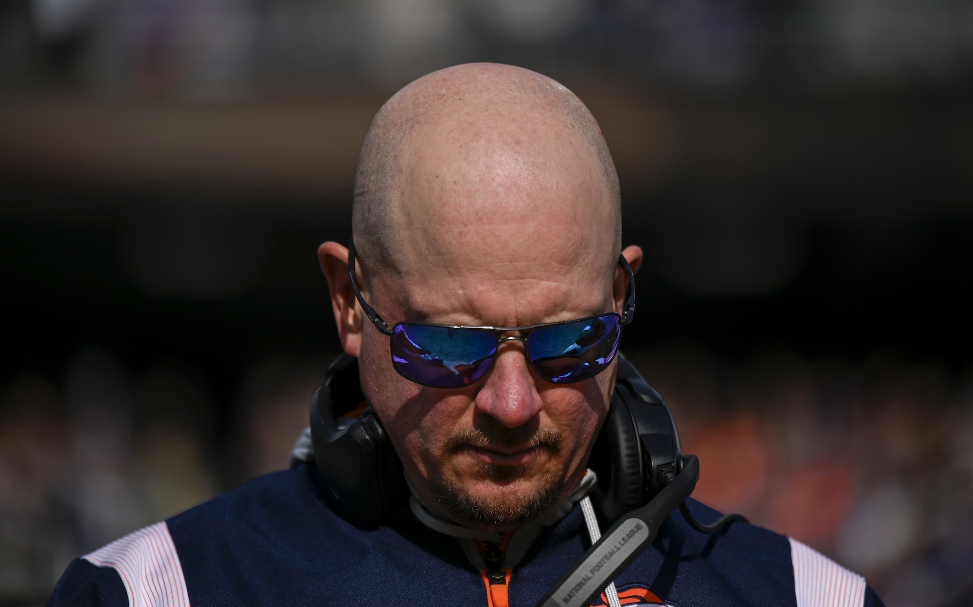 Nathaniel Hackett stands on the sideline in sunglasses during a Broncos-Ravens game.