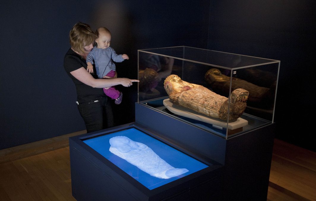 A woman encourages her child to look at the mummy of young boy during a preview of the 'Ancient lives, new discoveries' exhibition at the British Museum in Central London on May 20, 2014.