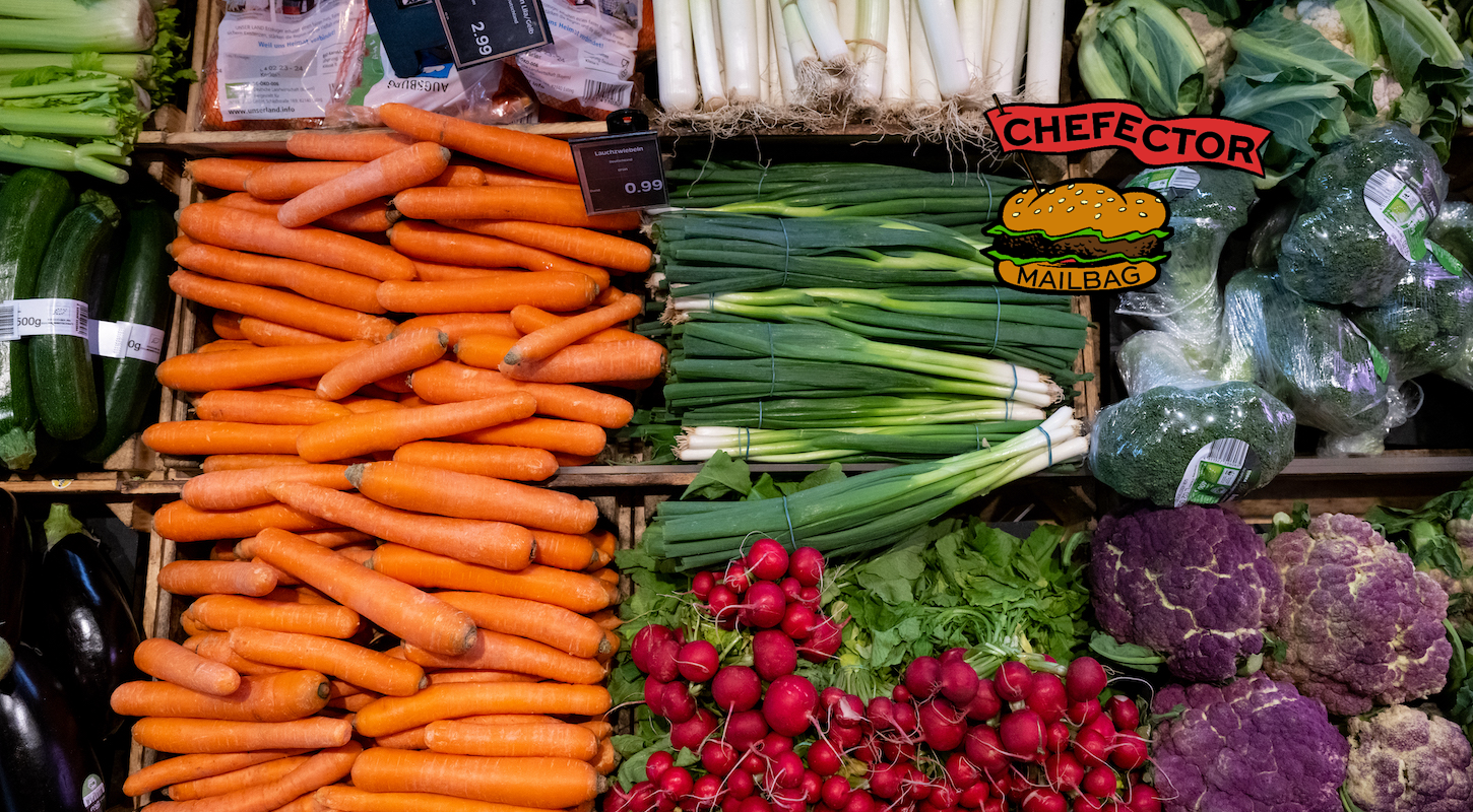 A vegetable grocery display with carrots and scallions and radishes