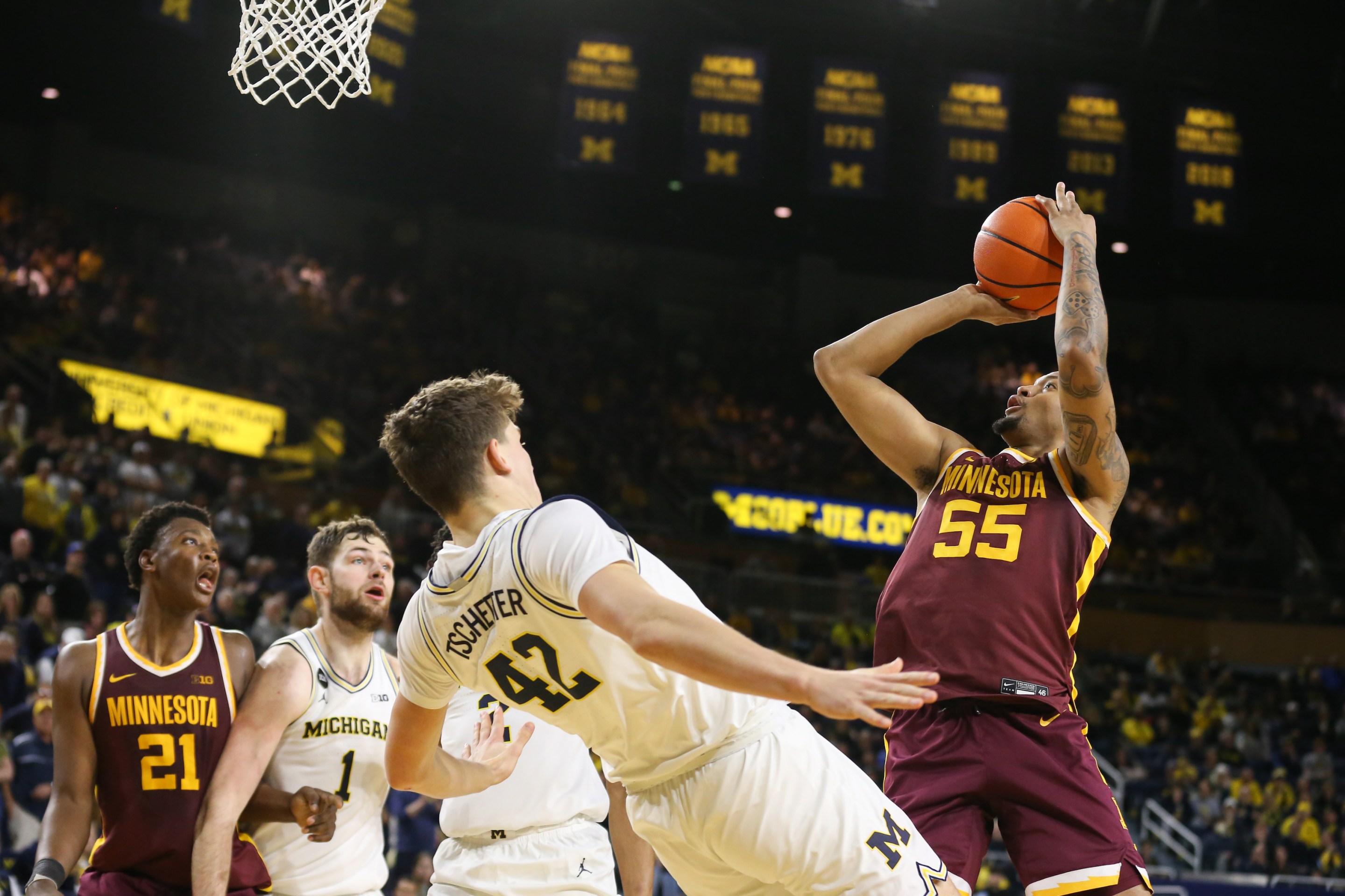 Michigan defender Will Tschetter draws a charge against Minnesota guard Ta'lon Cooper in a Big Ten game in Ann Arbor, Mi.