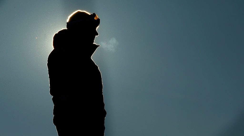 United States snowboard coach Peter Foley looks on in the Men's Slopestyle Qualification during the Sochi 2014 Winter Olympics at Rosa Khutor Extreme Park on February 6, 2014 in Sochi, Russia. He is backlit, standing in silhouette.