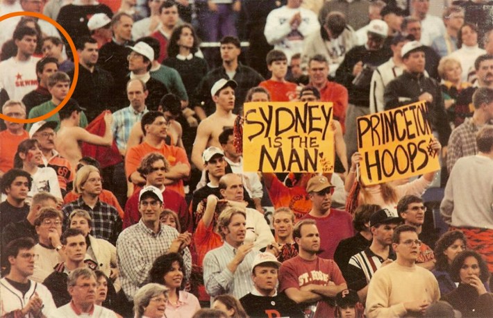 A bunch of Princeton fans; two have SYDNEY is the MAN and PRINCETON HOOPS signs. Jon Solomon, in a SWKM soccer jersey, is in the background circled in Princeton Tiger orange.