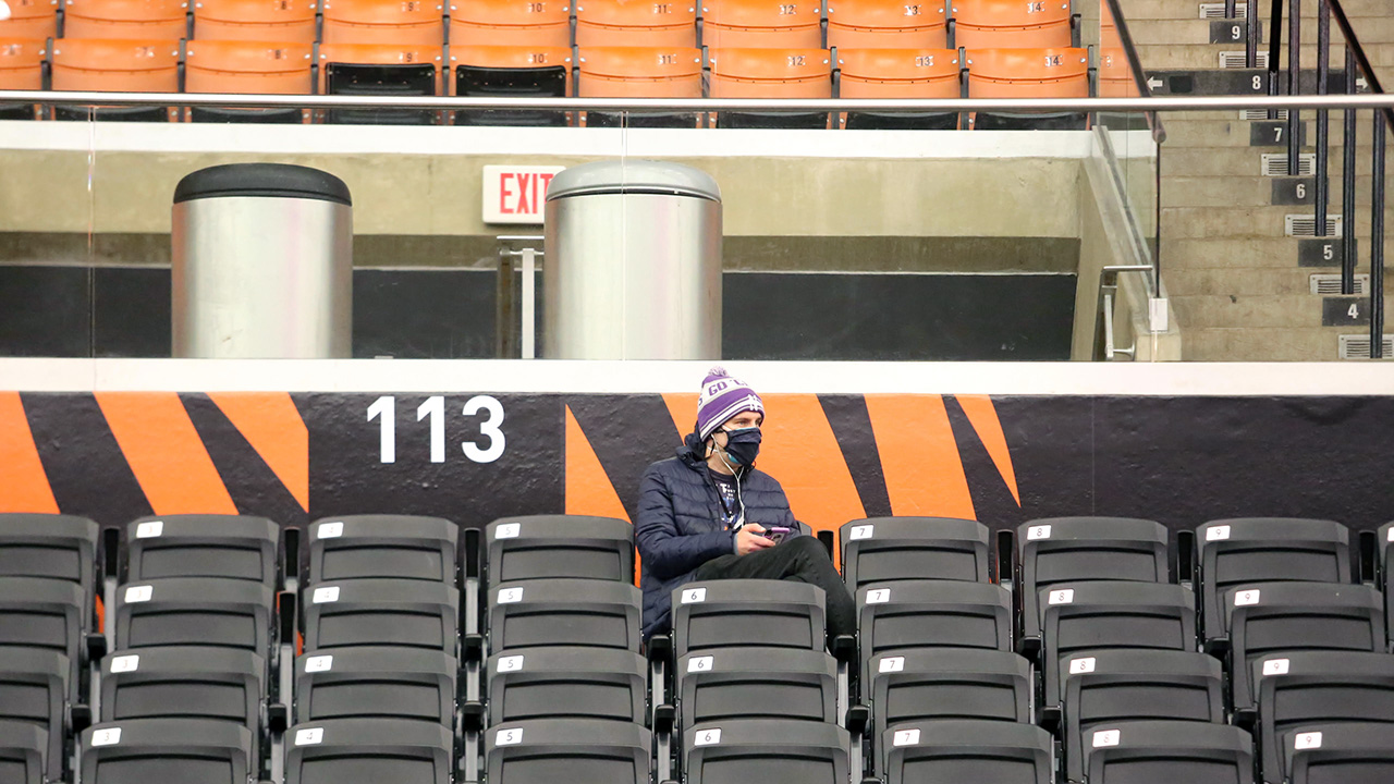 Jon Solomon (masked) sits in a sea of empty black chairs in Section 113 at Jadwin Gym in Princeton.