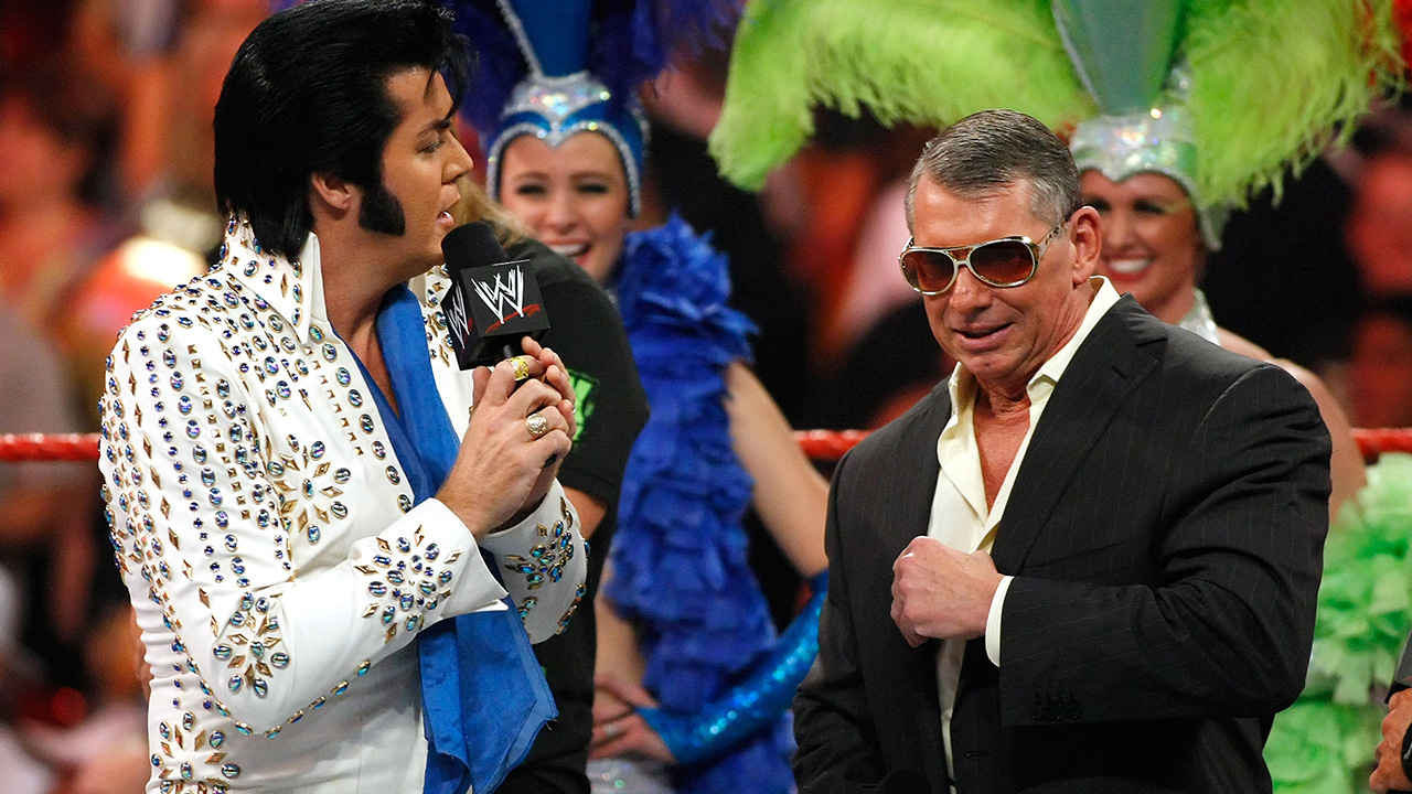 LAS VEGAS - AUGUST 24: An Elvis Presley impersonator sings to World Wrestling Entertainment Inc. Chairman Vince McMahon during his 64th birthday celebration in the ring during the WWE Monday Night Raw show at the Thomas & Mack Center August 24, 2009 in Las Vegas, Nevada.