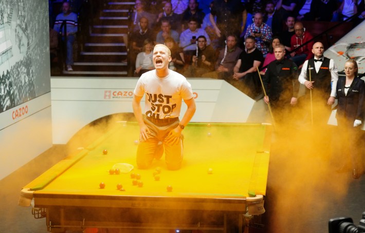 A protester explodes a bag of orange powder atop a billiard table. 