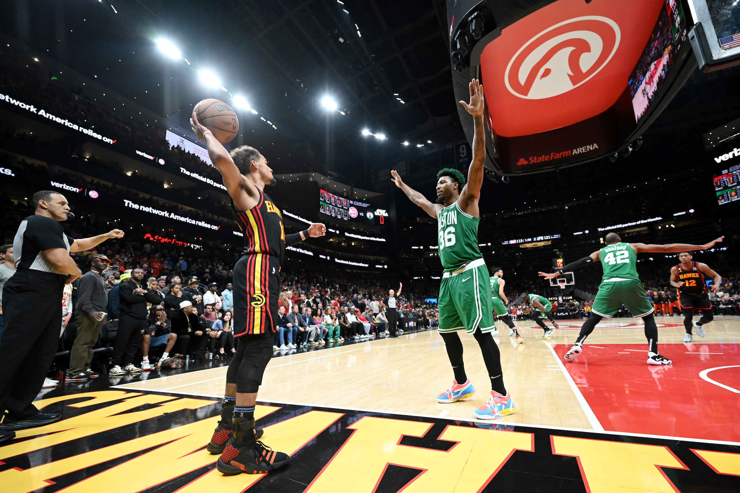 Trae Young prepares to inbound the ball, defended by Marcus Smart.