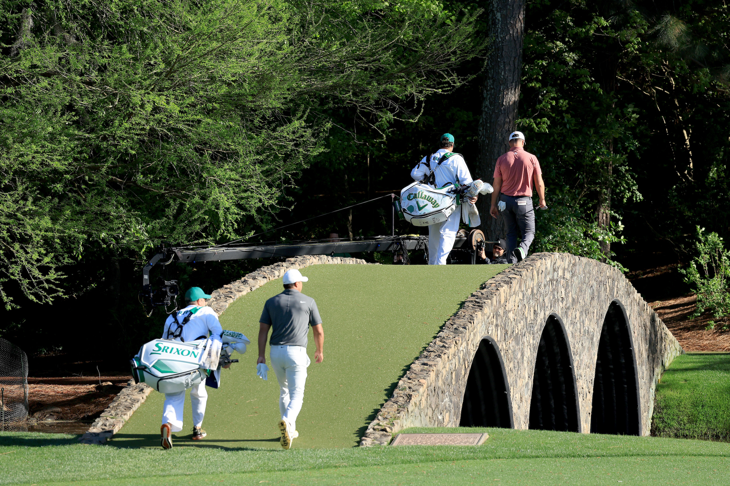 Jon Rahm and Brooks Koepka walk over a footbridge on the course.