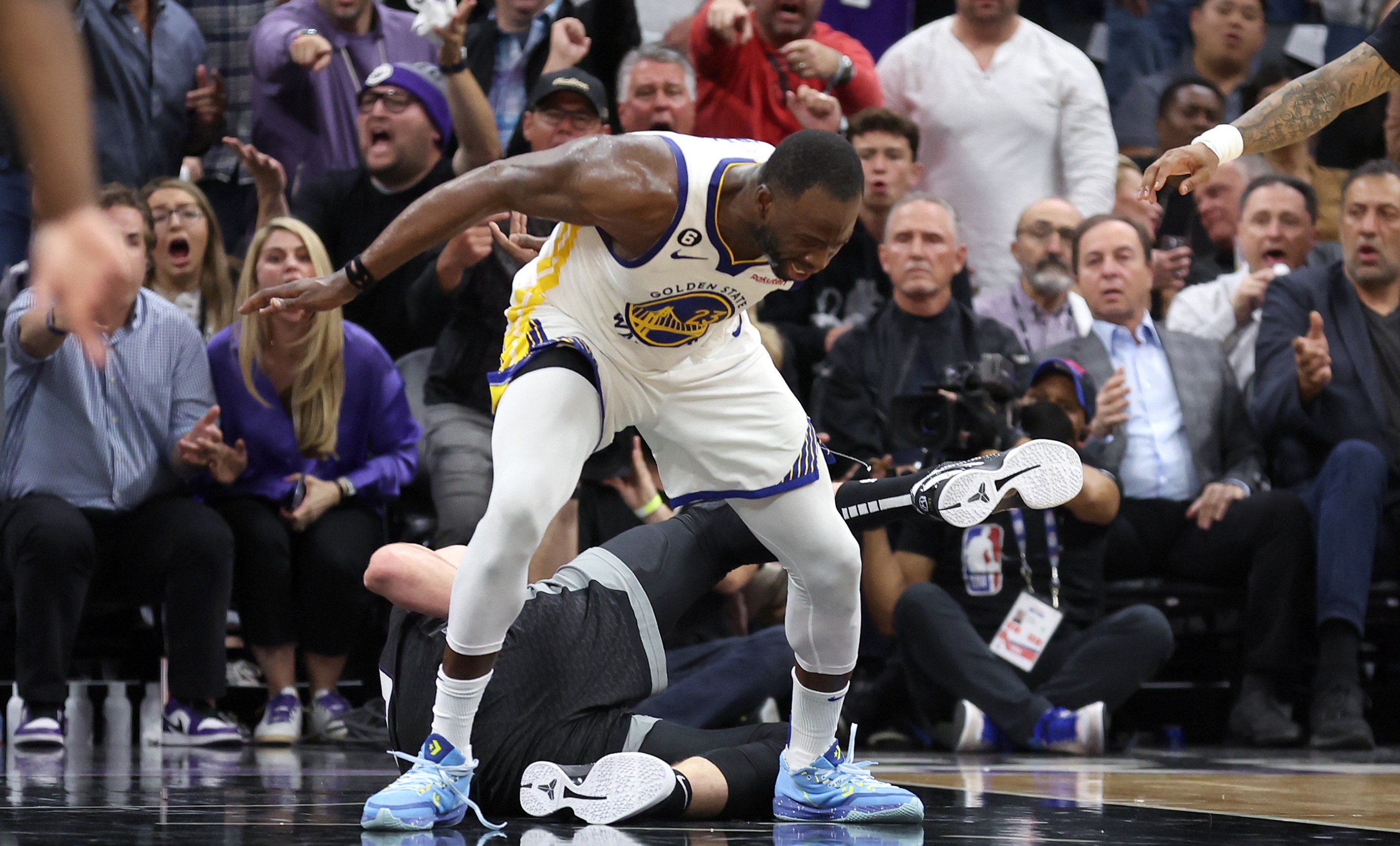 SACRAMENTO, CALIFORNIA - APRIL 17: Draymond Green #23 of the Golden State Warriors steps over Domantas Sabonis #10 of the Sacramento Kings in the second half during Game Two of the Western Conference First Round Playoffs at Golden 1 Center on April 17, 2023 in Sacramento, California. Green was issued a flagrant foul 2 on the play, and ejected from the game. NOTE TO USER: User expressly acknowledges and agrees that, by downloading and or using this photograph, User is consenting to the terms and conditions of the Getty Images License Agreement. (Photo by Ezra Shaw/Getty Images)