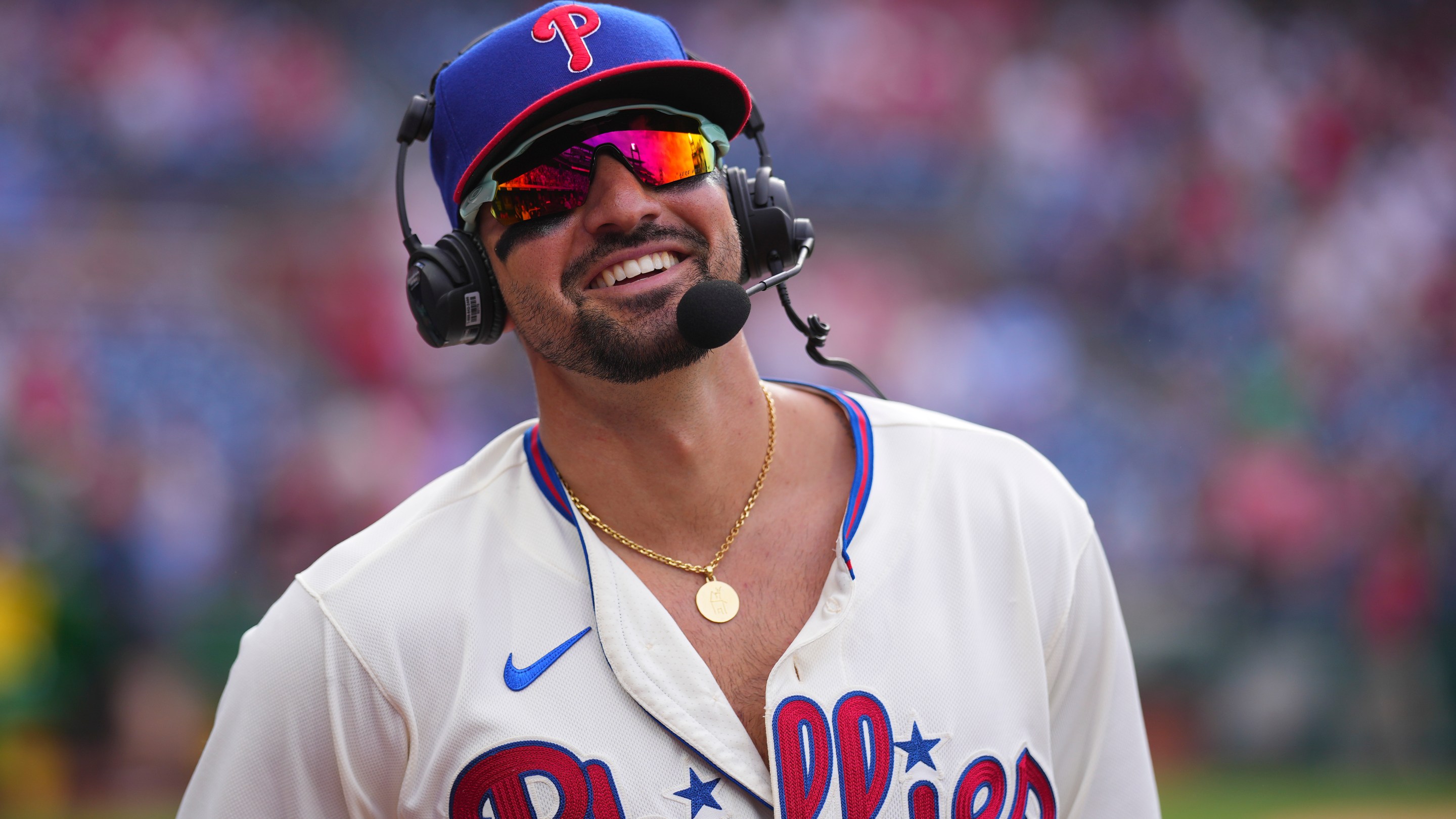 Nick Castellanos #8 of the Philadelphia Phillies smiles during his postgame interview, wearing both a headset and giant sunglasses