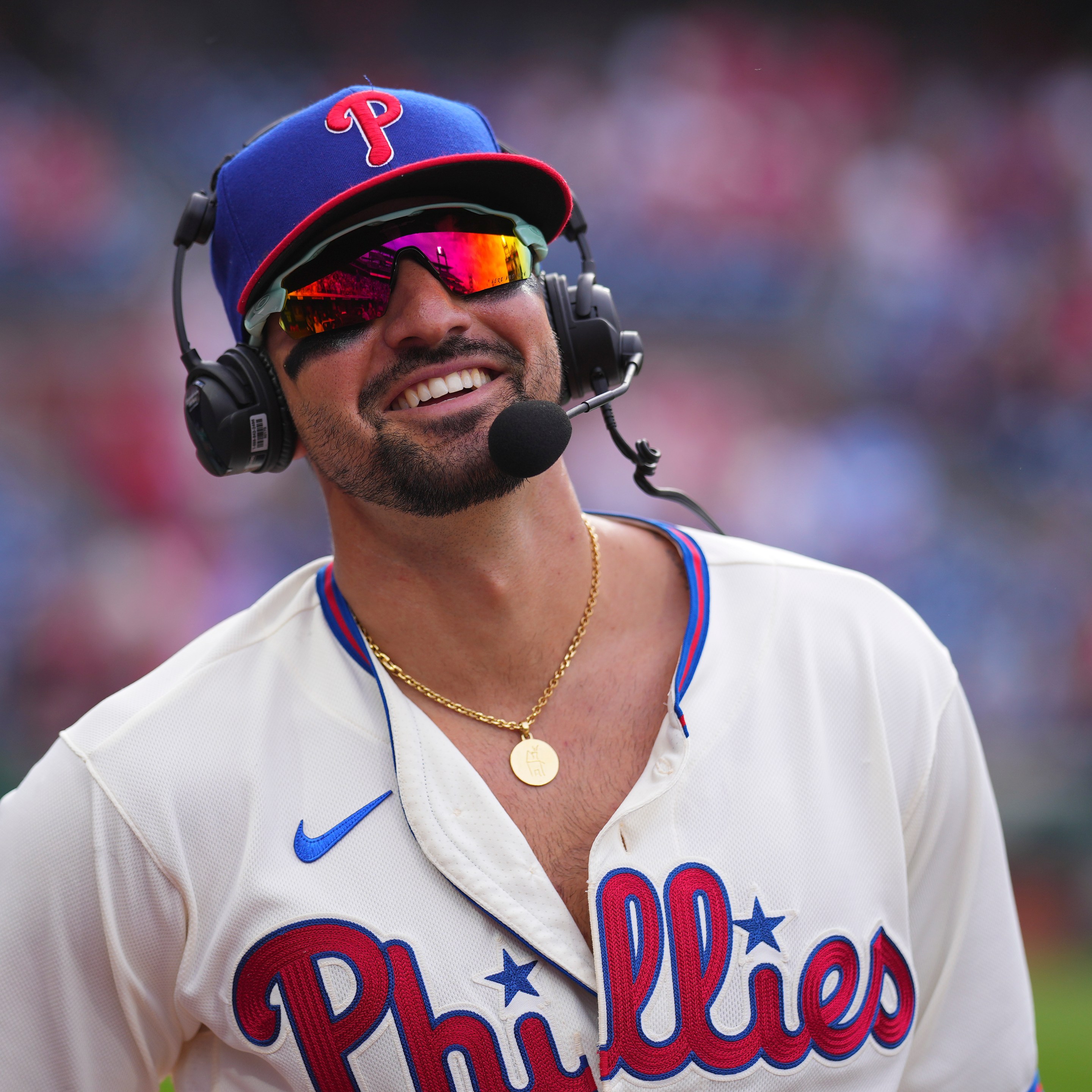 Nick Castellanos #8 of the Philadelphia Phillies smiles during his postgame interview, wearing both a headset and giant sunglasses