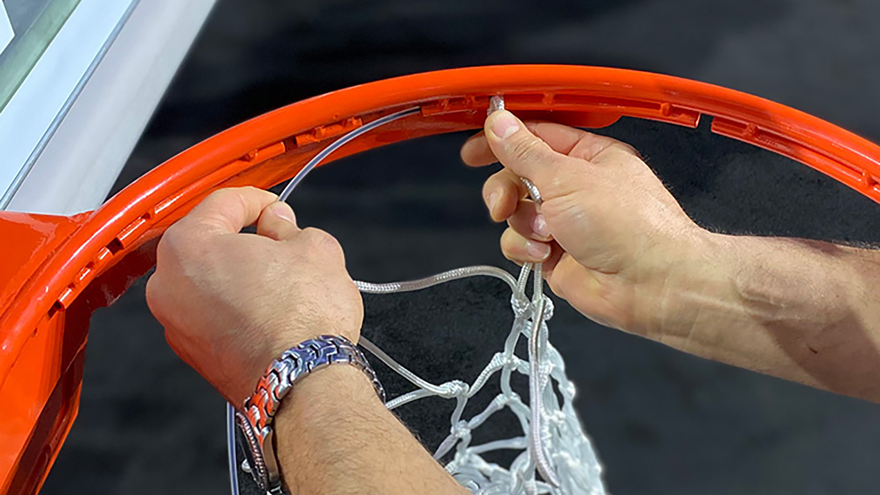 Two hands string a wire into the net