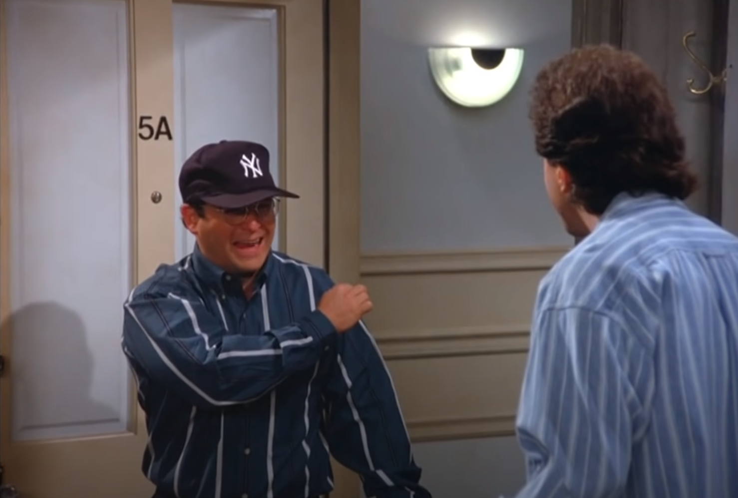 George exults while wearing a Yankees cap after being hired as the assistant to the traveling secretary for the New York Yankees in an episode of "Seinfeld."