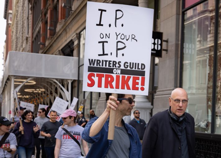 A member of Writers Guild of America participates in a march on a picket line in front of Netflix offices. After contract negotiations failed, thousands of unionized writers voted unanimously to strike, bringing television production to a halt, and initiating the first walkout in 15 years.