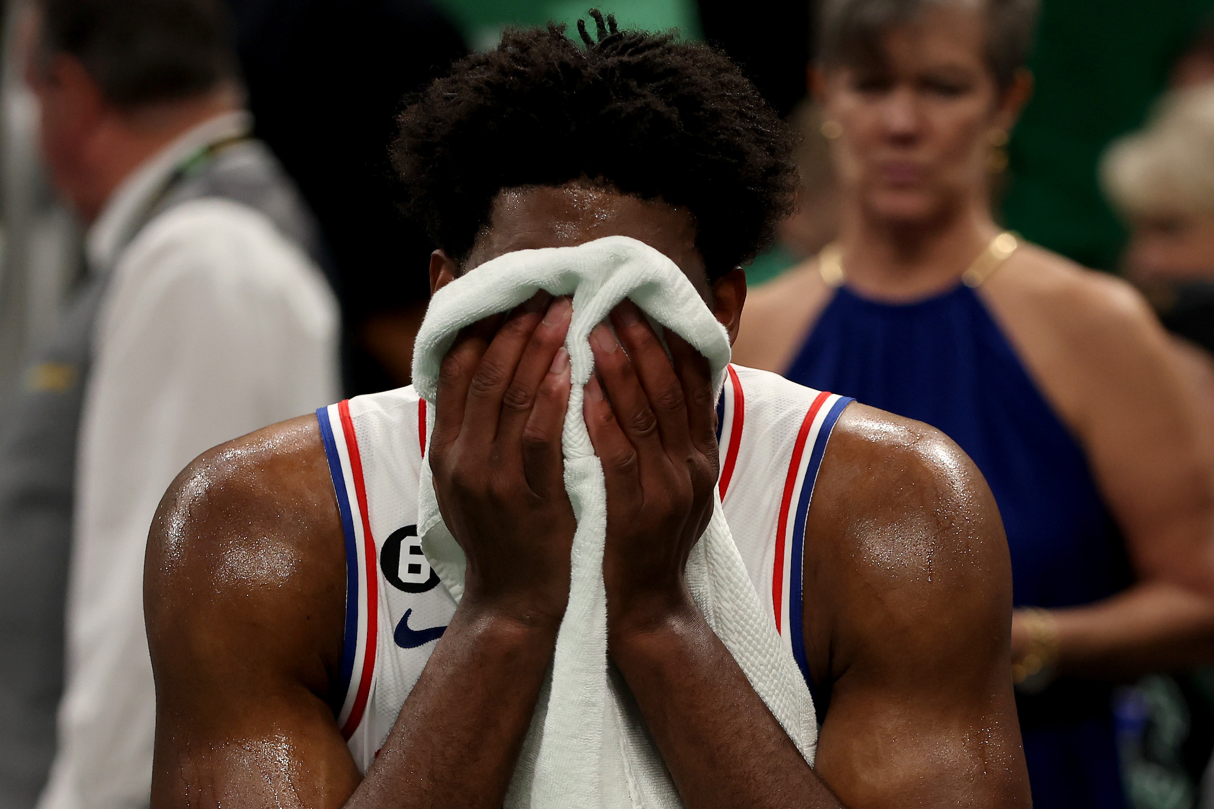 Joel Embiid covers his face with a towel.