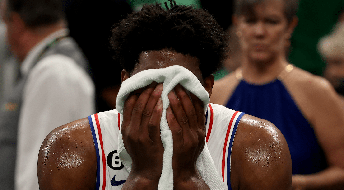 Joel Embiid covers his face with a towel