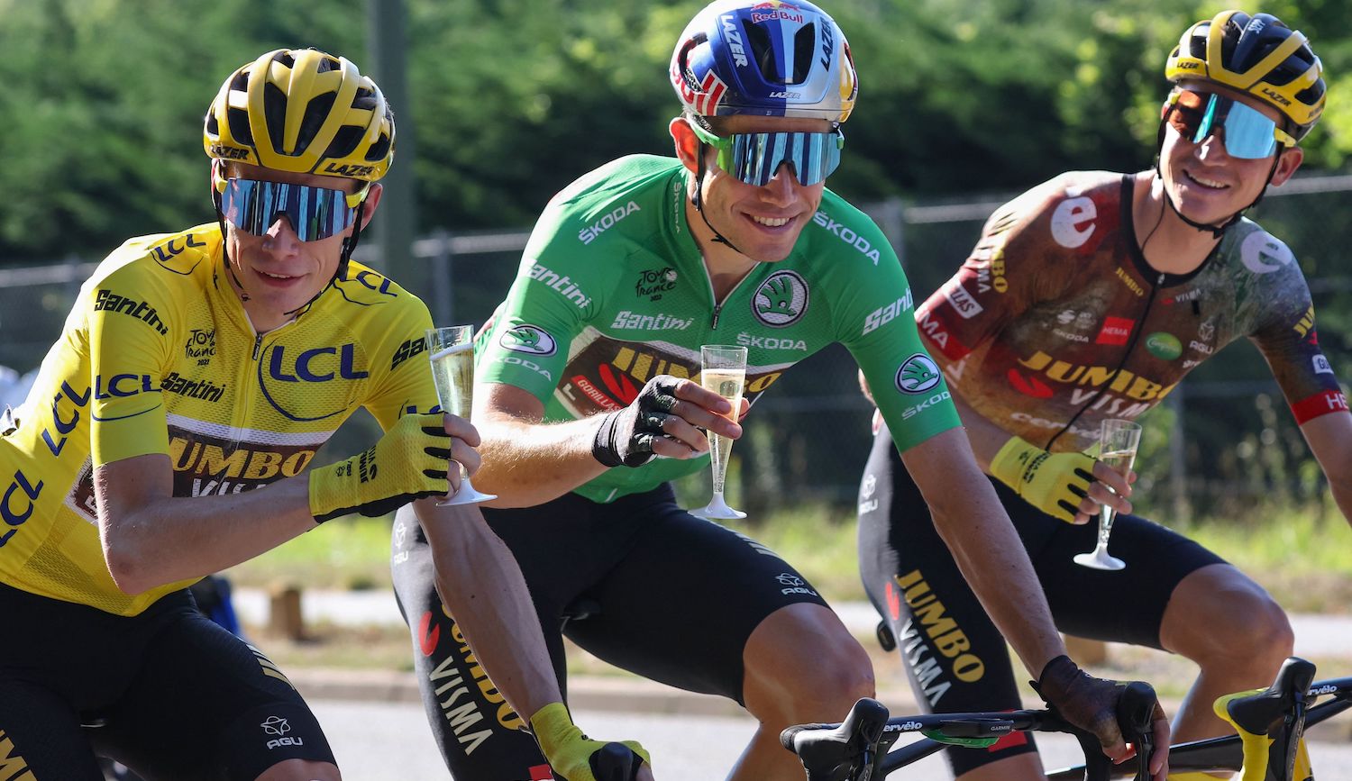 TOPSHOT - Jumbo-Visma team's Danish rider Jonas Vingegaard wearing the overall leader's yellow jersey (C), Jumbo-Visma team's Belgian rider Wout Van Aert wearing the sprinter's green jersey (C) and Jumbo-Visma team's American rider Sepp Kuss (R) celebrate with champagne as they cycle during the 21st and final stage of the 109th edition of the Tour de France cycling race, 115,6 km between La Defense Arena in Nanterre, outside Paris, and the Champs-Elysees in Paris, France, on July 24, 2022. (Photo by Thomas SAMSON / various sources / AFP) (Photo by THOMAS SAMSON/AFP via Getty Images)