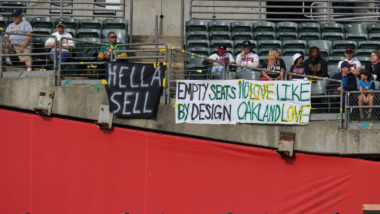 OAKLAND, CALIFORNIA - MAY 29: Fans sit behind signs referencing plans for the Oakland Athletics to move to Las Vegas during a game against the Atlanta Braves at RingCentral Coliseum on May 29, 2023 in Oakland, California.