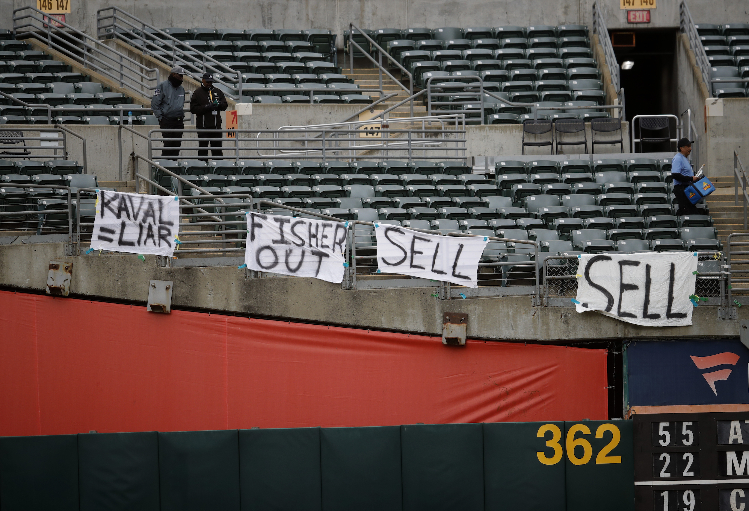 Fans hang signs at Oakland Coliseum calling for John Fisher to sell the Athletics.
