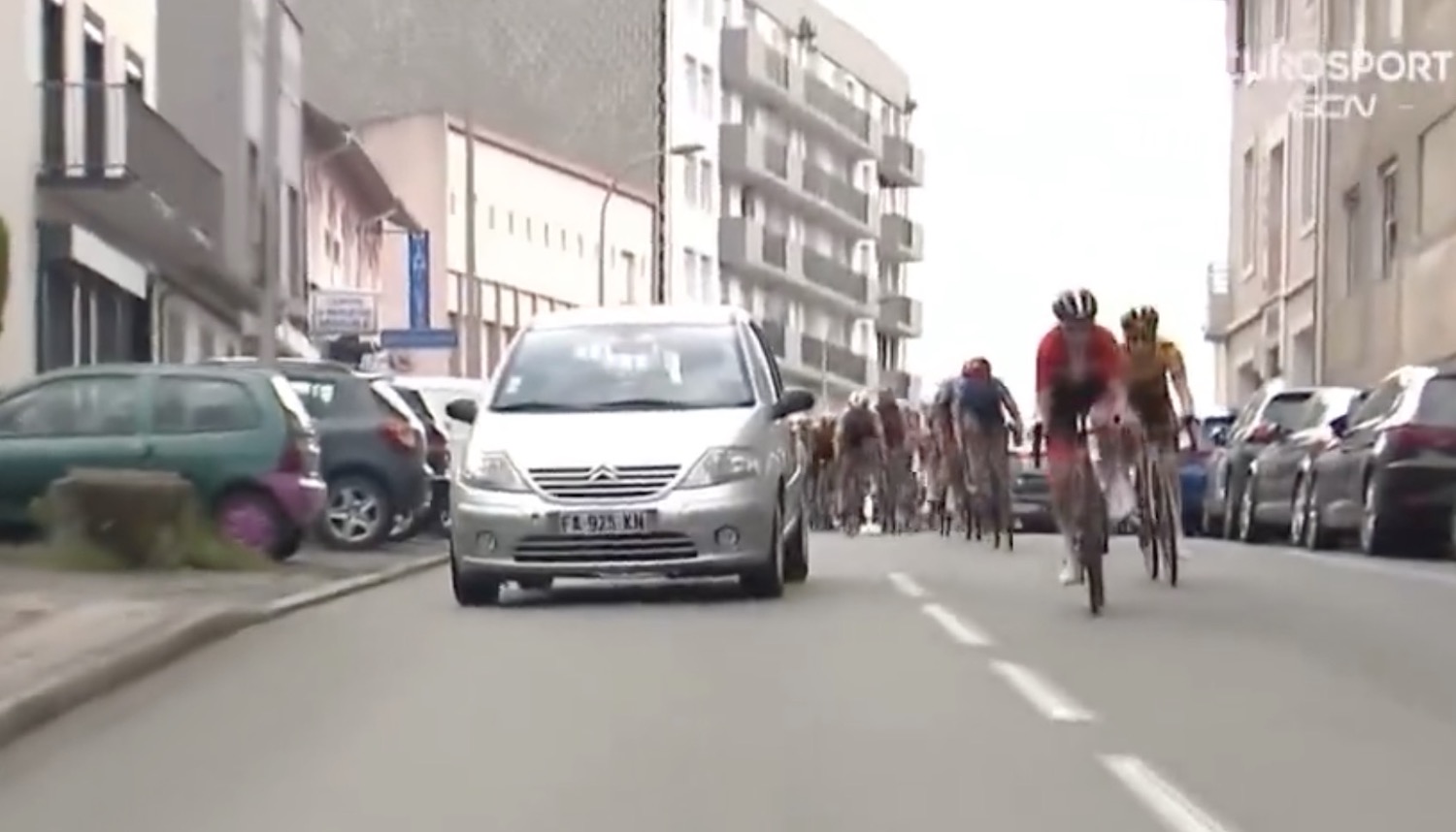 Riders shake their heads in confusion as they pass a car on the race course.