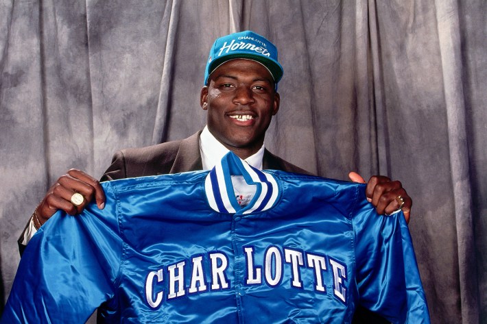 Larry Johnson holds up a satin Charlotte Hornets jacket after being picked first in the NBA Draft