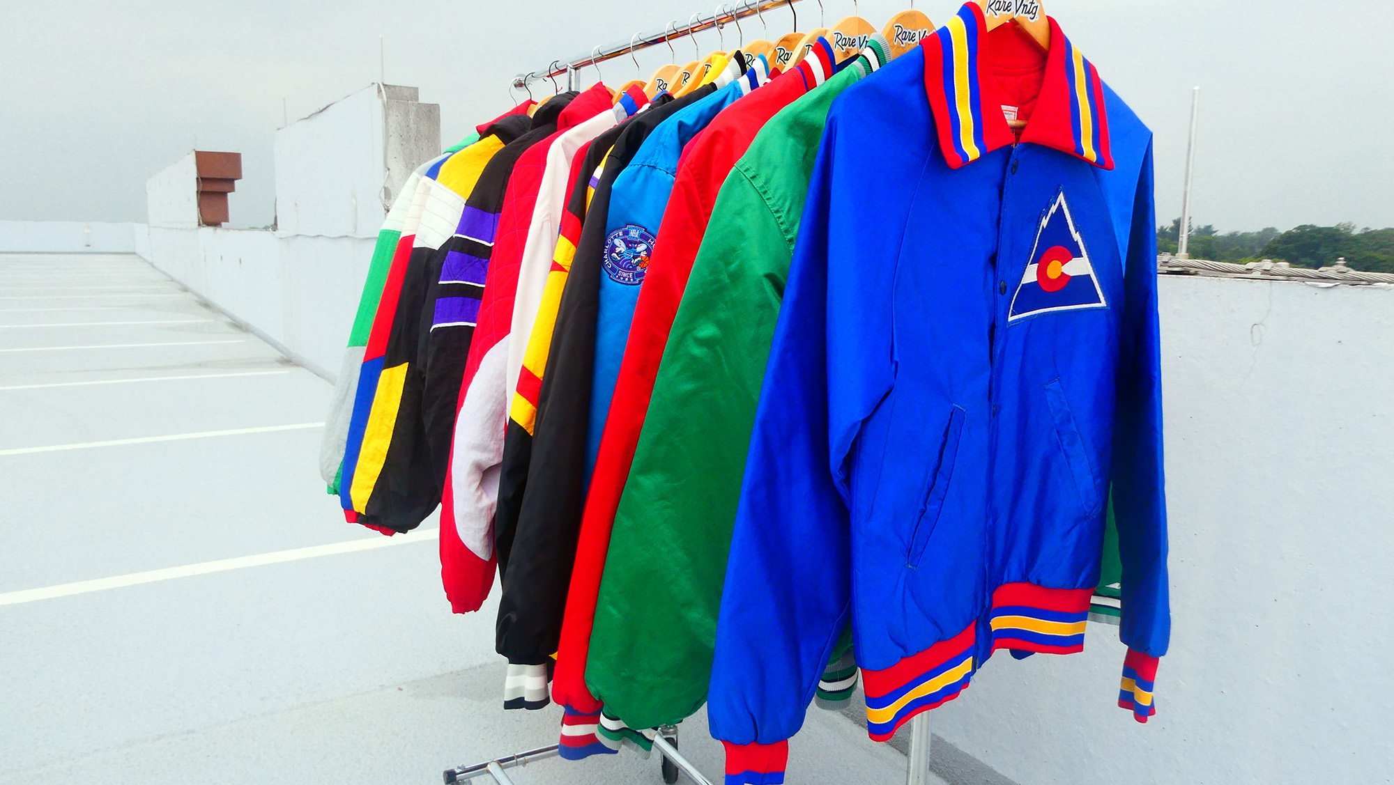 A rack of Starter jackets, satin and pullover and polyester. Colorado Rockies is in the front.