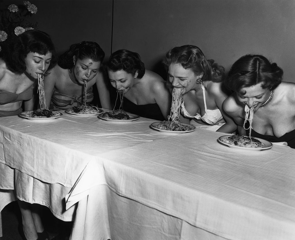 Broadway showgirls (from left) Geraldine Shay, Pat Gale, Bonnie Blair, Genne Courtney and Toni Tucci eat spaghetti with their arms held behind their backs, as part of some sort of competition. 1948.