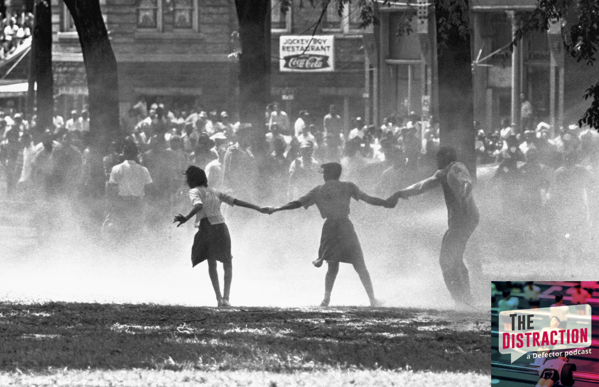 Three demonstrators join hands to build strength against the force of water sprayed by riot police in Birmingham, Alabama, during a protest of segregation practices.