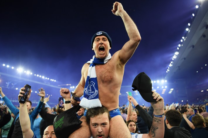 Everton fans celebrate on the pitch following their sides victory as they avoid relegation after the Premier League match between Everton and Crystal Palace at Goodison Park on May 19, 2022 in Liverpool, England.