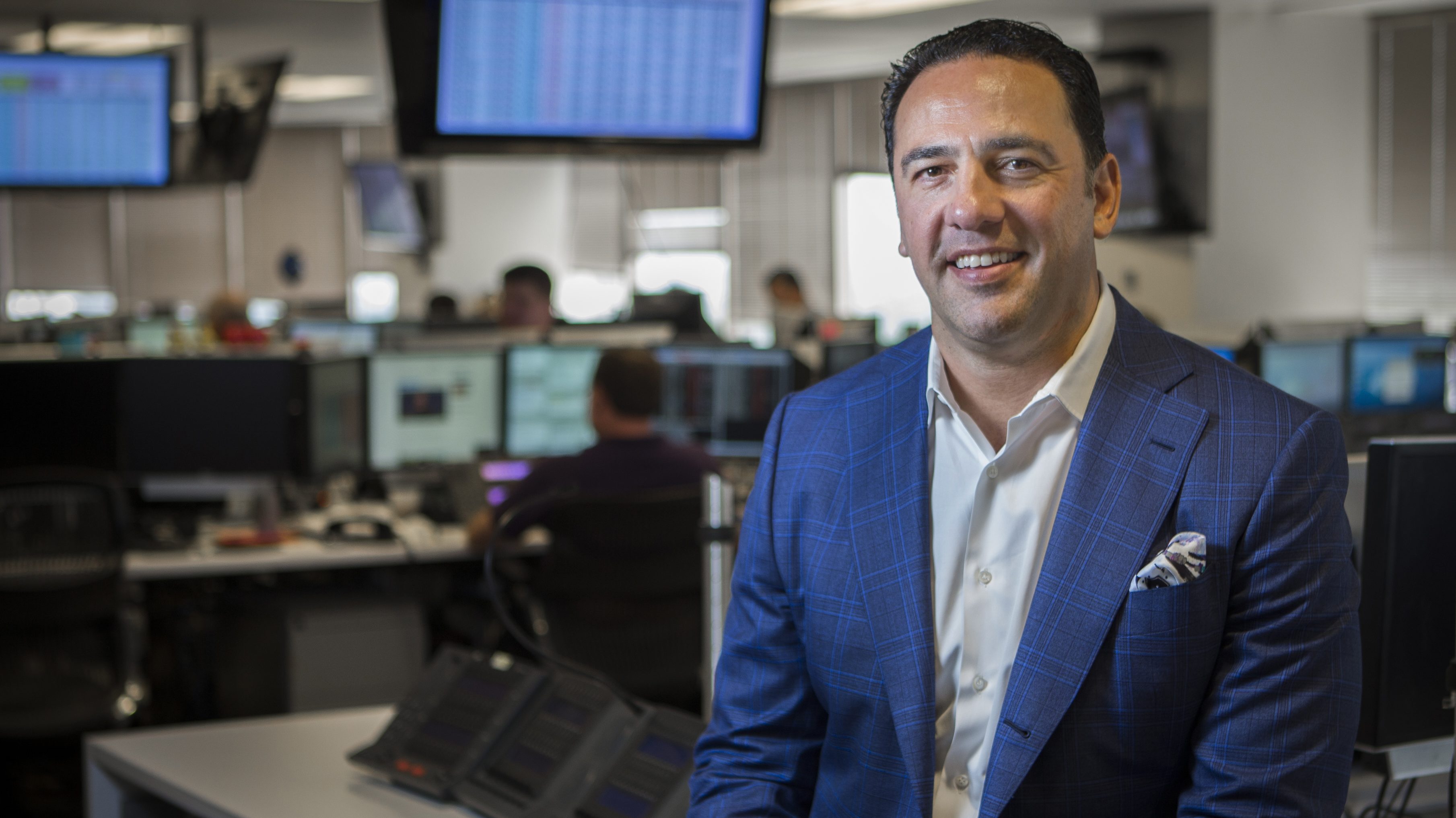 A photo of E. Javier Loya, wearing a business suit in the office of OTC Global Holdings, a company he co-founded.