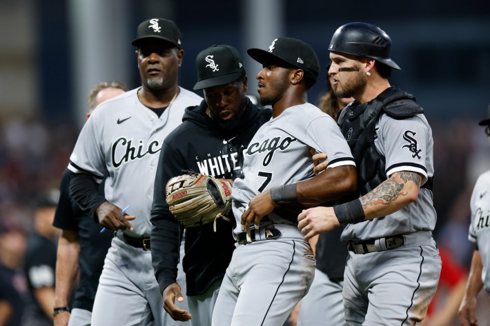 Tim Anderson is either "restrained" or "held upright" by teammates after getting socked by José Ramirez.
