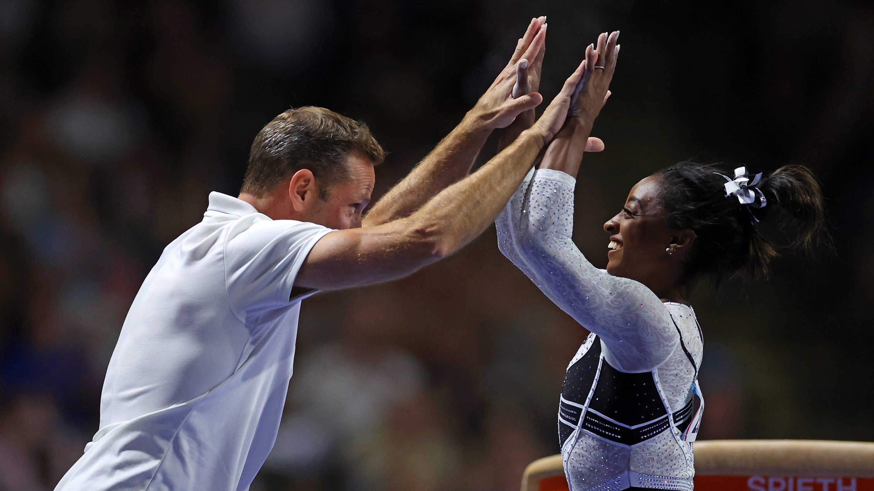 Simone Biles celebrates with her coach Laurent Landi after competing on the vault at the Core Hydration Classic at Now Arena on August 05, 2023 in Hoffman Estates, Illinois.