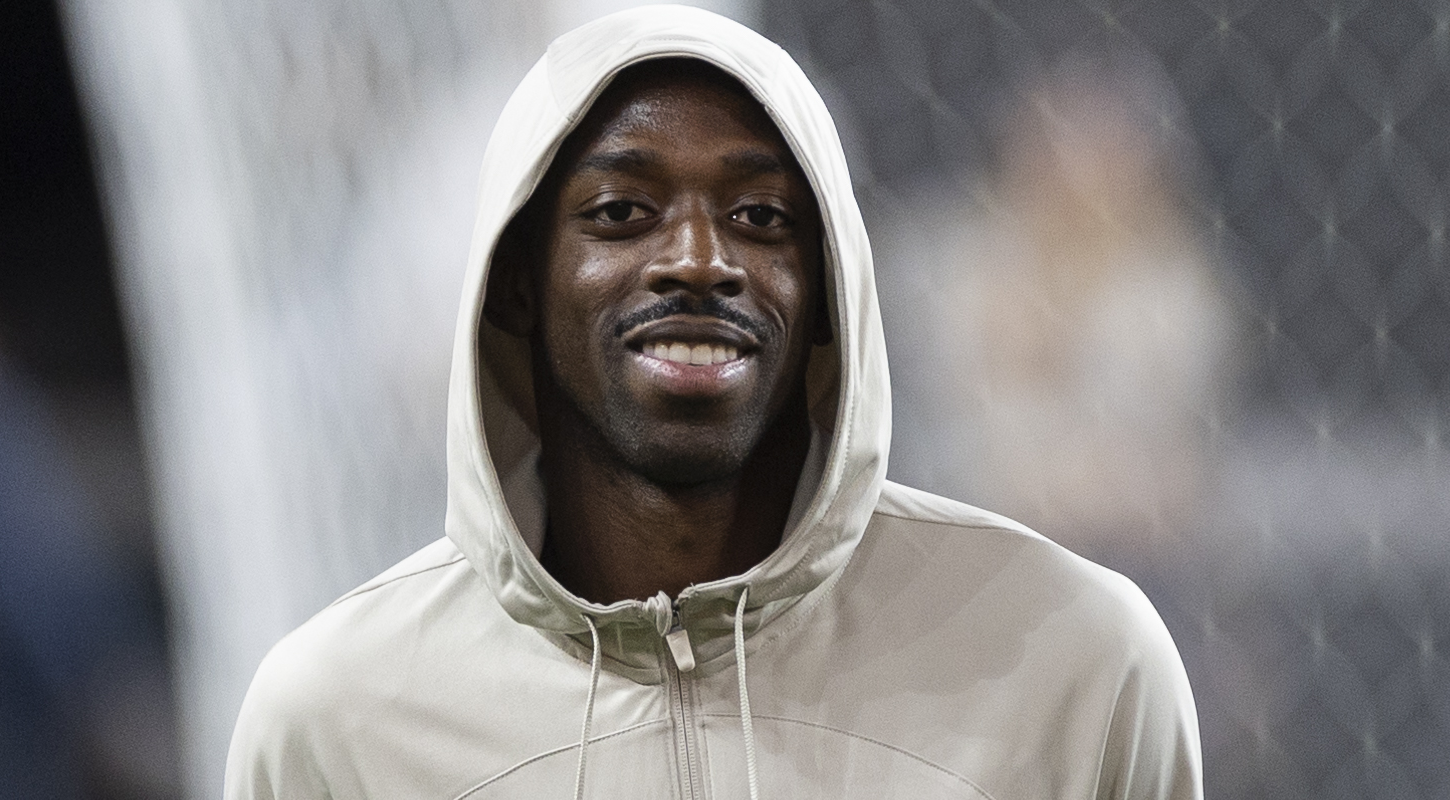 Ousmane Dembélé in a Barcelona hoodie, smiling.