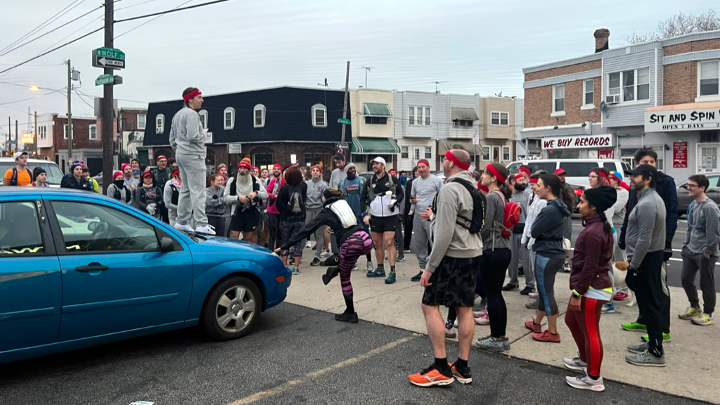 Bunch of people dressed like Rocky, woman standing on a blue car talking to them