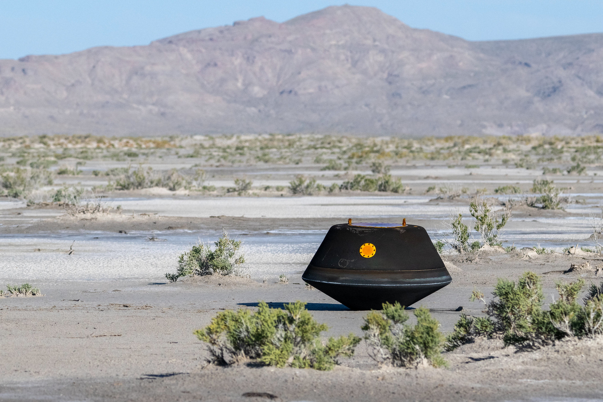A photo of a black UFO looking thing in the desert
