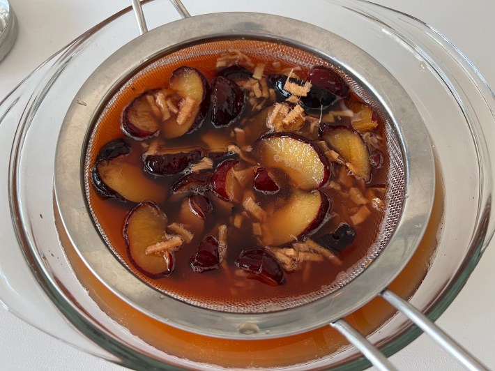 A sieve strains the fruit out of the syrup.