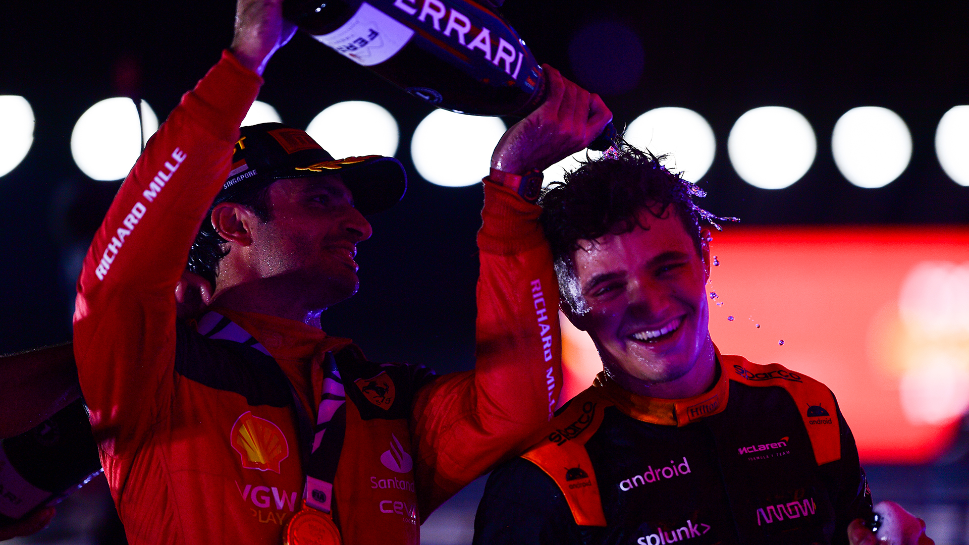 Race winner Carlos Sainz of Spain and Ferrari celebrates with Second placed Lando Norris of Great Britain and McLaren on the podium during the F1 Grand Prix of Singapore at Marina Bay Street Circuit on September 17, 2023 in Singapore, Singapore.