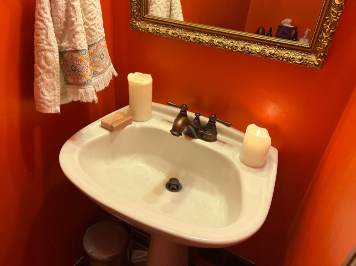 A small bathroom sink with two burning pillar candles.