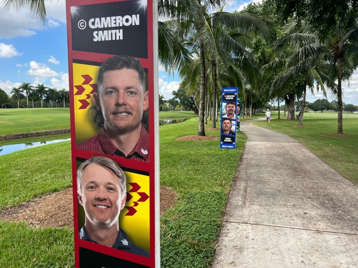 A sign along a cart path shows the faces of Cameron Smith and Matt Jones of Ripper GC.