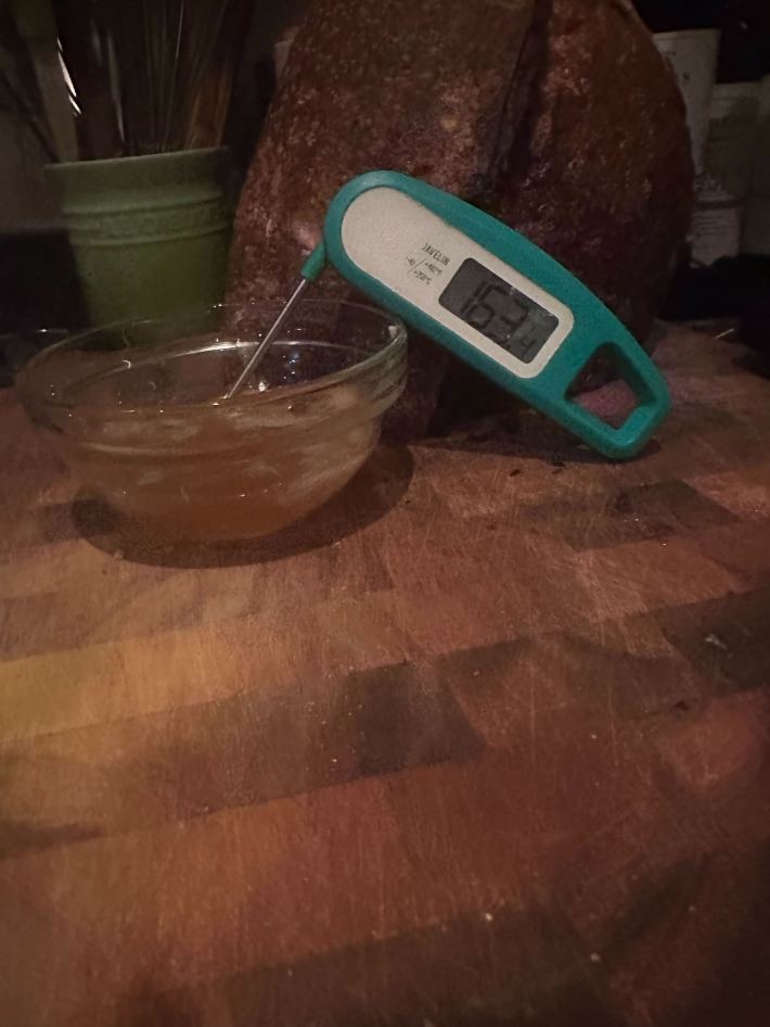 Using an instant-read digital meat thermometer to check the temperature of sugar syrup.