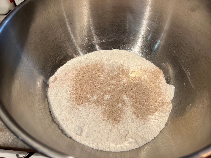 Bread flour, salt, and dry fast-action yeast haphazardly share a large bowl.