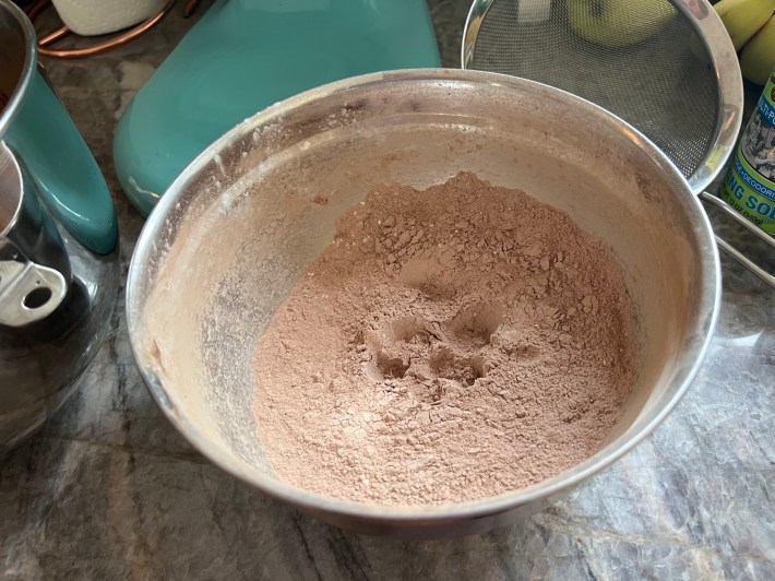A metal mixing bowl of sifted flour and cocoa, from which a black beetle has recently been rescued.