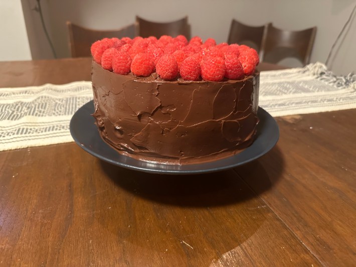 Kelsey's finished cake, with remarkably straight sides, glossy icing, and plump raspberries.