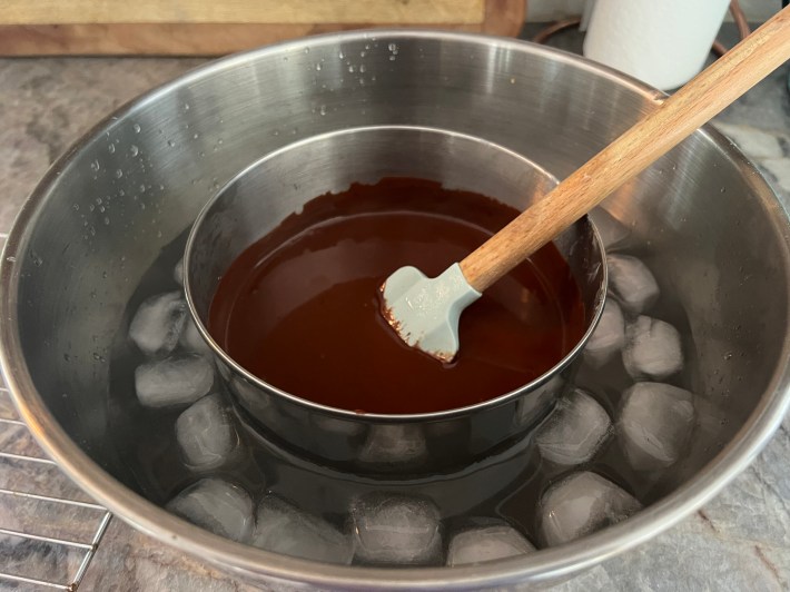 Liquid ganache in a mixing bowl, resting inside of a larger mixing bowl half-filled with salted ice-water.