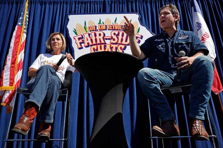 DeSantis sits on a stool outdoors. Once again his lower leg appears abnormally long, with an extra bend toward the bottom.