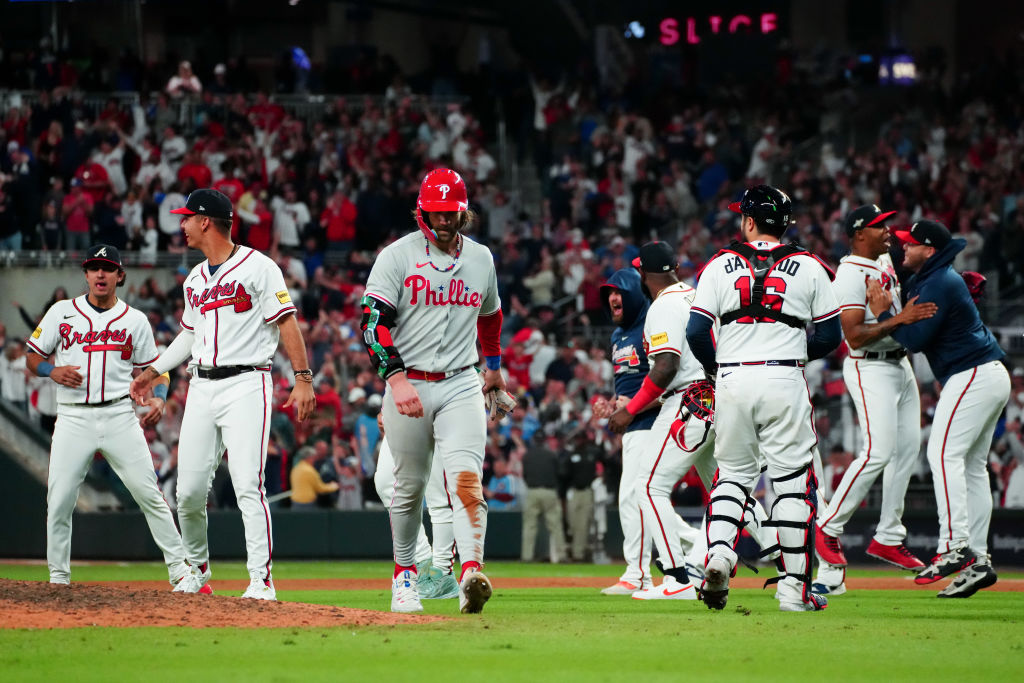 Bryce Harper walks back to the dugout as the Atlanta Braves celebrate their win