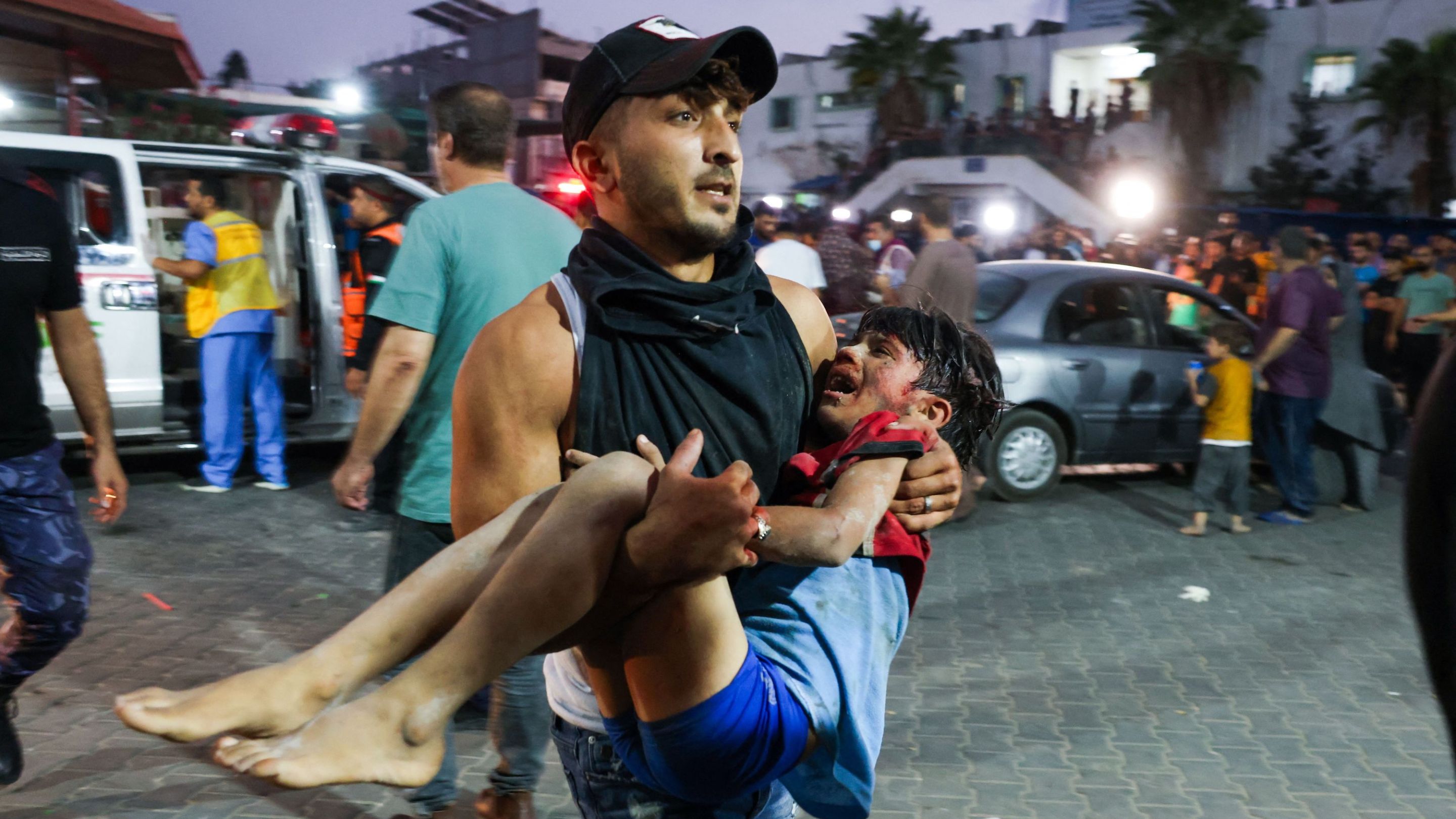 A man carries a child, wounded by Israeli airstrikes, into Al-Shifa hospital in Gaza City