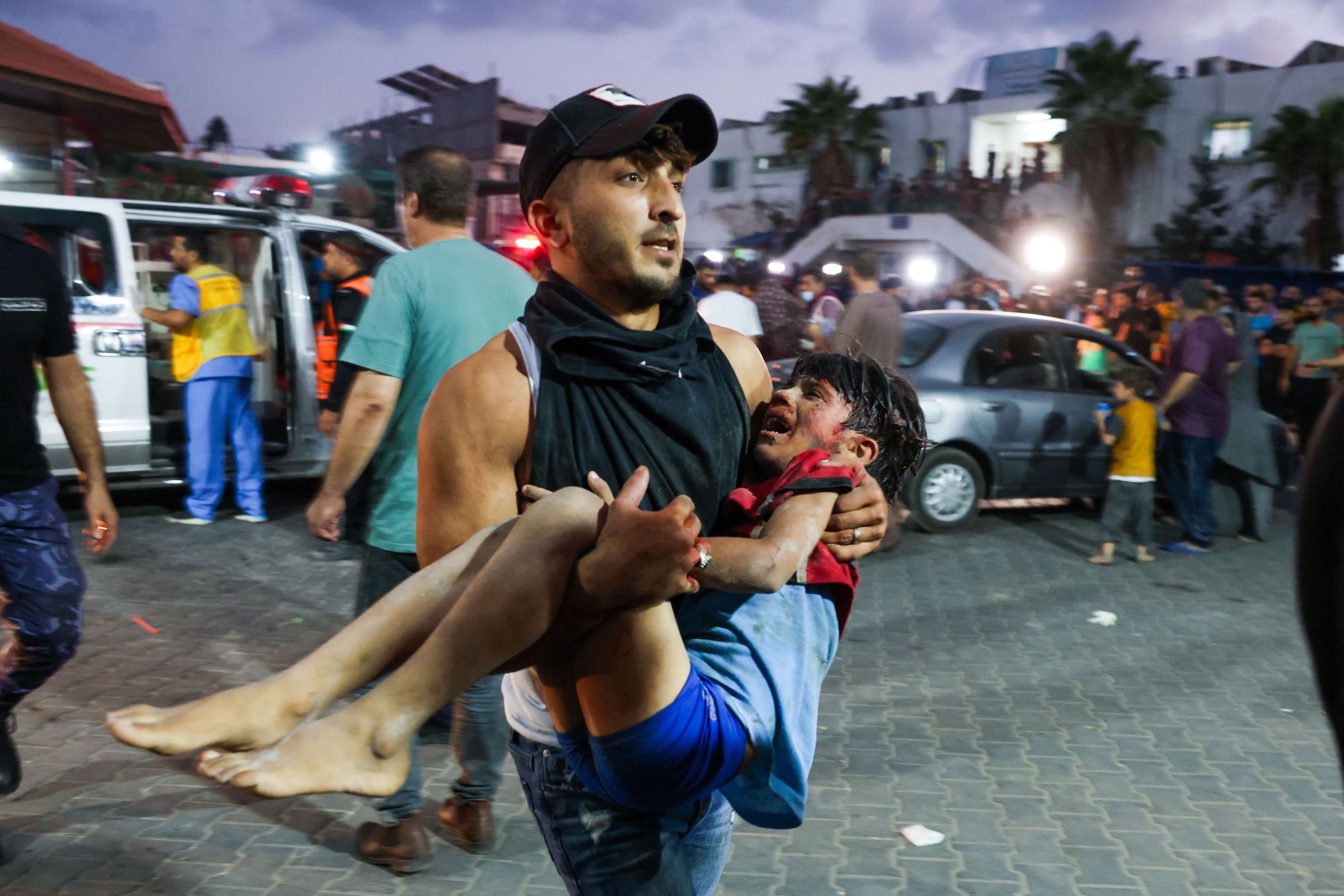 A man carries a child, wounded by Israeli airstrikes, into Al-Shifa hospital in Gaza City