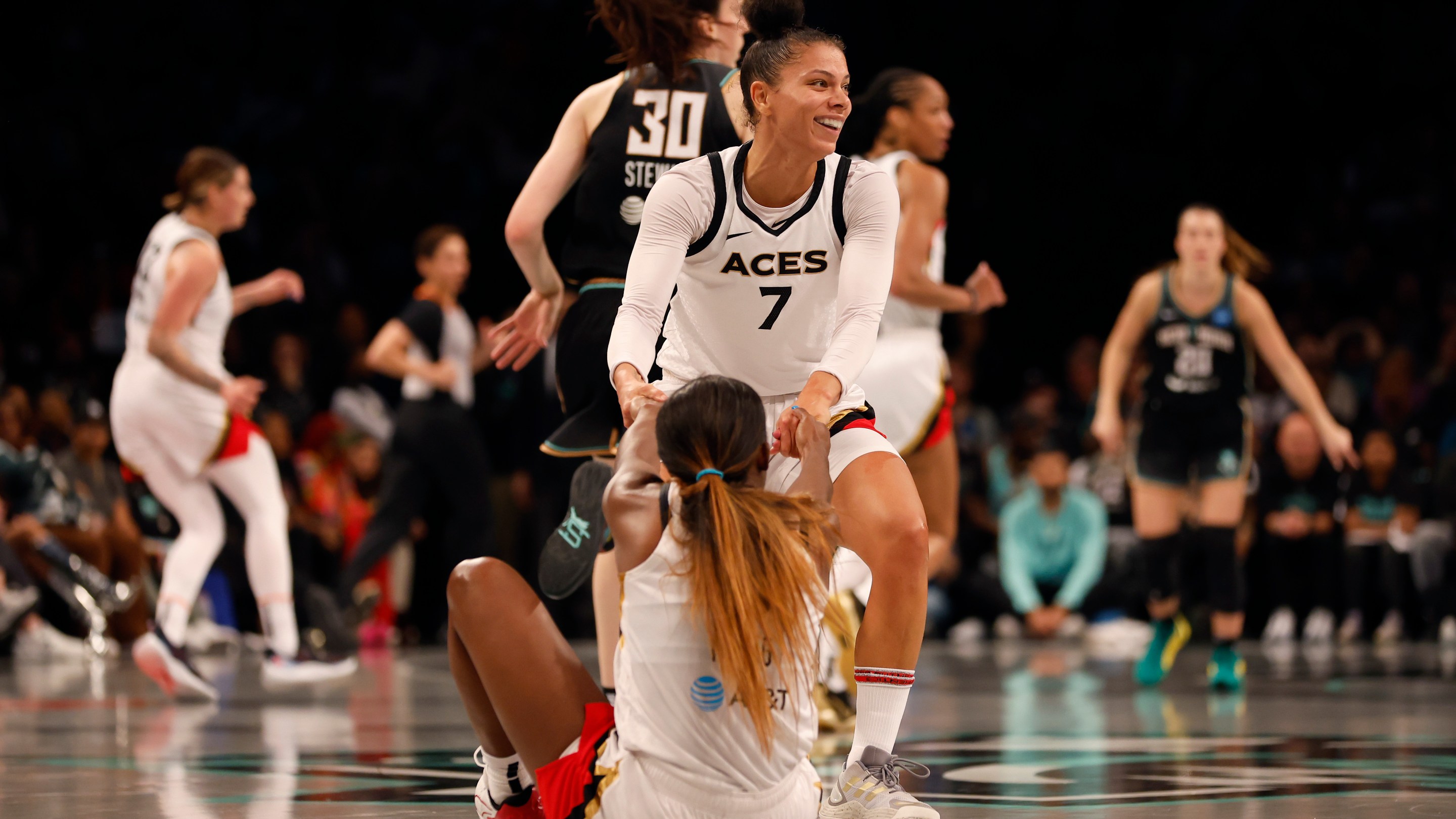 Alysha Clark #7 of the Las Vegas Aces helps teammate Jackie Young #0 up off the court in the second quater against the New York Liberty during Game Four of the 2023 WNBA Finals at Barclays Center on October 18, 2023 in New York City.